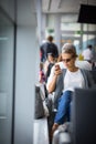 Young woman using her cell phone while waiting to board a plane at departure gates