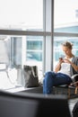 Casual blond young woman using her cell phone while waiting to board a plane