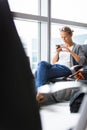 Casual blond young woman using her cell phone while waiting to board a plane