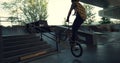 Casual bmx rider performing tricks on ramp with bike at city skate park.