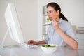 Casual brunette businesswoman eating a salad at her desk Royalty Free Stock Photo
