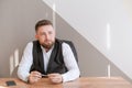 Casual business man bearded, sitting at table with pen in his hand, thinking