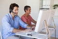 Casual business team working at desk using computers with man using headset Royalty Free Stock Photo