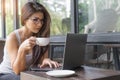 Casual business woman working on laptop. Young girl using computer outdoor drinking coffee in cafe. Royalty Free Stock Photo