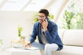 Casual businessman sitting on the couch at home while making a call and taking notes on notepad Royalty Free Stock Photo