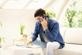 Casual businessman sitting on the couch at home while making a call and taking notes on notepad Royalty Free Stock Photo