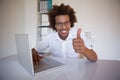 Casual businessman smiling at camera at his desk showing thumbs up Royalty Free Stock Photo