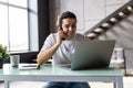 Casual businessman working at office desk, using mobile phone and laptop computer, typing, making phone call Royalty Free Stock Photo