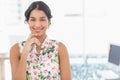 Hispanic woman standing at office desk by large window with potted plant, in floral blouse, smiling Royalty Free Stock Photo