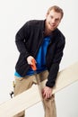 Casual carpenter. Portrait of a young carpenter sawing a piece of wood against his leg. Royalty Free Stock Photo