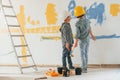 In casual clothes. Two boys painting walls in the domestic room