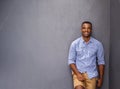 Casual confidence. A handsome young man leaning against a bluegray wall. Royalty Free Stock Photo