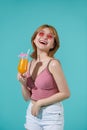 Casual dressed woman holding orange juice with glass, isolated portrait smiling girl on turquoise background Royalty Free Stock Photo