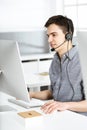 Casual dressed young man using headset and computer while talking with customers online. Call center, business concept Royalty Free Stock Photo