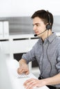 Casual dressed young man using headset and computer while talking with customers online. Call center, business concept Royalty Free Stock Photo