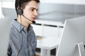 Casual dressed young man using headset and computer while talking with customers online. Call center, business concept Royalty Free Stock Photo