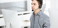 Casual dressed young man using headset and computer while talking with customers online. Call center, business concept Royalty Free Stock Photo