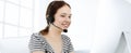 Casual dressed young woman using headset and computer while talking with customers online. Call center, business concept Royalty Free Stock Photo