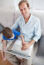 Casual father and son using laptop on the couch Royalty Free Stock Photo