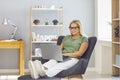 Casual female blonde manager working on laptop sitting on comfortable chair in modern bright office. Royalty Free Stock Photo
