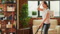 Casual girl using vacuum cleaner to tidy up apartment Royalty Free Stock Photo