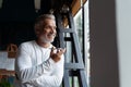 Casual Grey-haired Mature businessman talking on a mobile phone standing by the window. Royalty Free Stock Photo