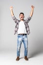 Casual handsome young man shouting for joy raising his hands above his head isolated on white background Royalty Free Stock Photo