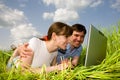 Casual happy couple on laptop computer outdoors