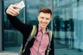 Casual happy young man in plaid shirt making selfie outdoors. Royalty Free Stock Photo