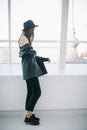 Casual hipster style young woman portrait. girl standing near the window in full growth. Soft daylight. Relaxed mood Royalty Free Stock Photo