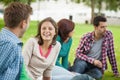 Casual laughing students sitting on the grass chatting