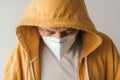 Casual male with yellow hooded jacket wearing protective respiratory KN95 face mask during covid-19