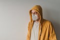 Casual male with yellow hooded jacket wearing protective respiratory KN95 face mask during covid-19