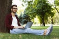 Man sitting on grass with laptop outdoors Royalty Free Stock Photo