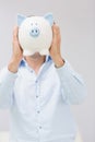 Casual man holding piggy bank in front of his face Royalty Free Stock Photo