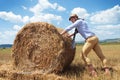 Casual man outdoor pushes a haystack Royalty Free Stock Photo