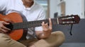 Casual man playing guitar while sitting on sofa at home. Royalty Free Stock Photo