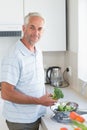 Casual man rinsing broccoli in colander and smiling at camera Royalty Free Stock Photo