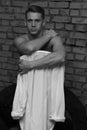 white young guy sitting on a chair near a gray brick wall, black-and-white photo Royalty Free Stock Photo