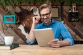 Casual man sitting at desk and looking at tablet happy