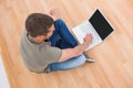 Casual man sitting on floor using laptop at home Royalty Free Stock Photo