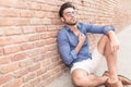 Casual man sitting near brick wall looking up Royalty Free Stock Photo