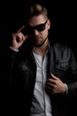 Casual man standing and fixing his sunglasses and jacket Royalty Free Stock Photo