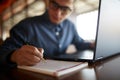 Close-up of man hand writing on paper notebook. Young businessman in glasses taking notes in notepad with stylish Royalty Free Stock Photo