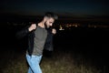 Casual man walks outdoor in the night and fixes collar Royalty Free Stock Photo