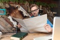 Casual man holding the newspaper while looking at camera happy