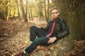 Casual man wearing a leather jacket, leaning on a tree Royalty Free Stock Photo