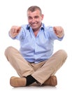 Casual middle aged man sits and points at you Royalty Free Stock Photo