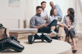 Casual multiethnic friends sitting on sofa with joysticks on foreground