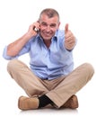 Casual old man sits and shows ok while on phone Royalty Free Stock Photo